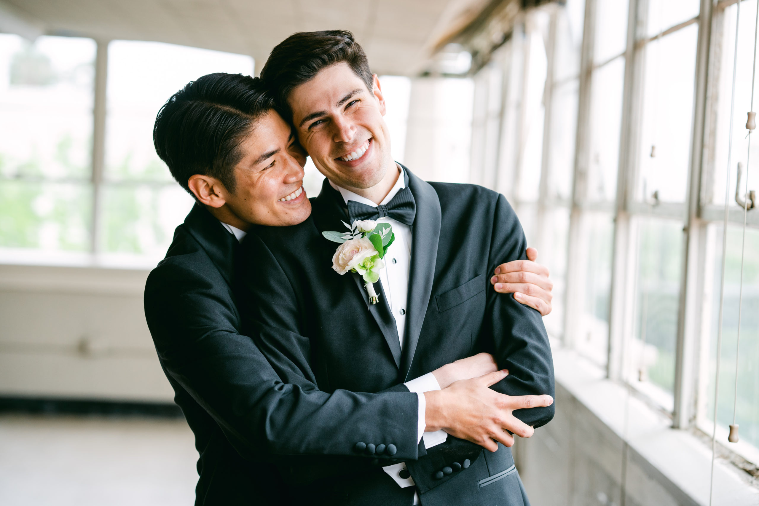 A Ebell Los Angeles wedding photo. Two grooms, Ian and Kenny, pose together. One hugging the other while he smiles at the camera.